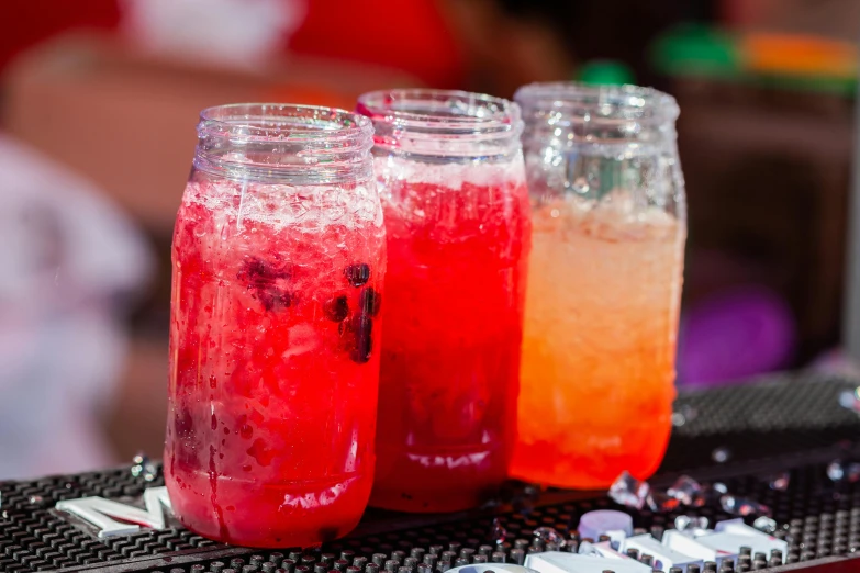 three jars filled with red, pink and yellow drinks