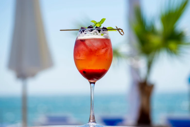 a tall glass filled with ice and garnish on a table