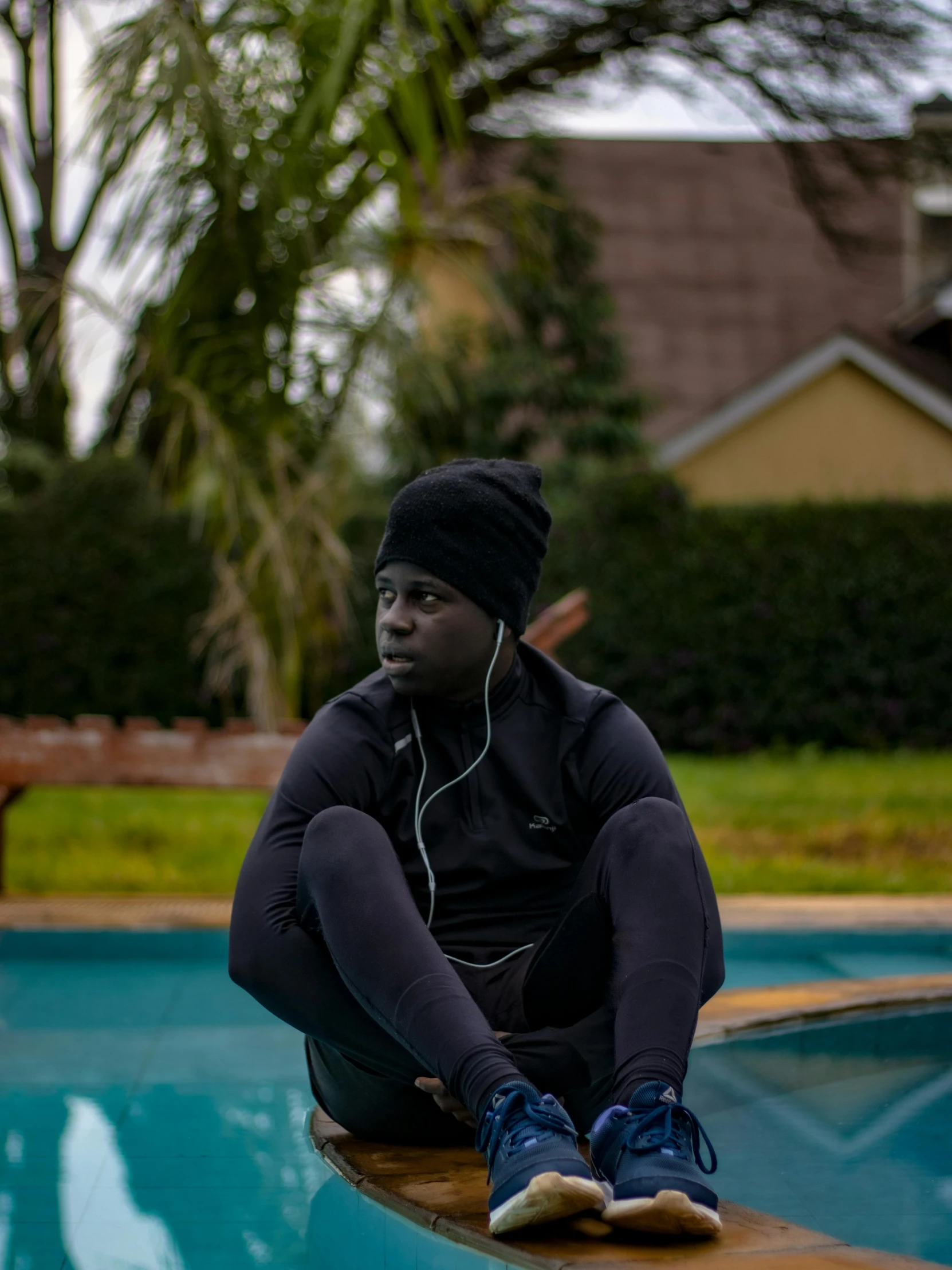 a young man is sitting on the edge of a pool