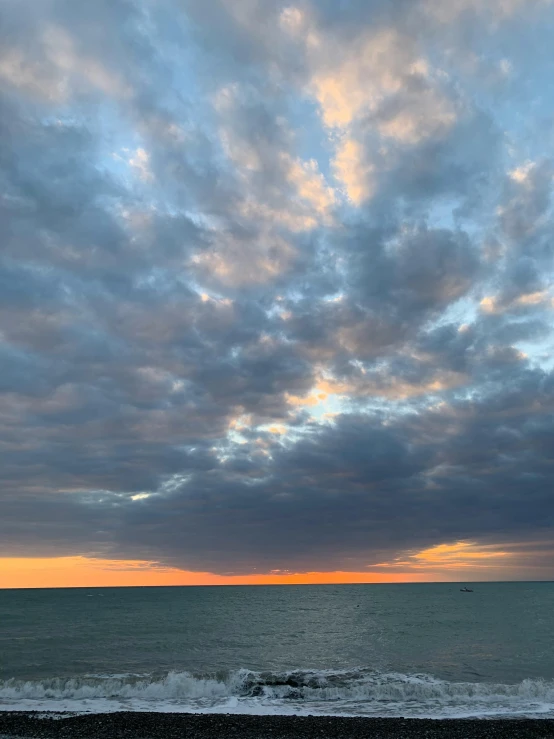 a blue ocean with white clouds, and a bench