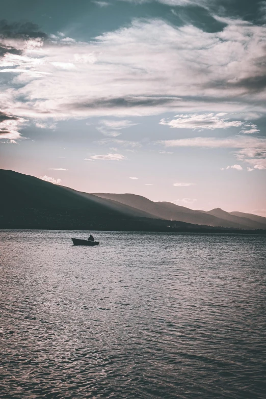 a small boat on the water under a cloudy sky