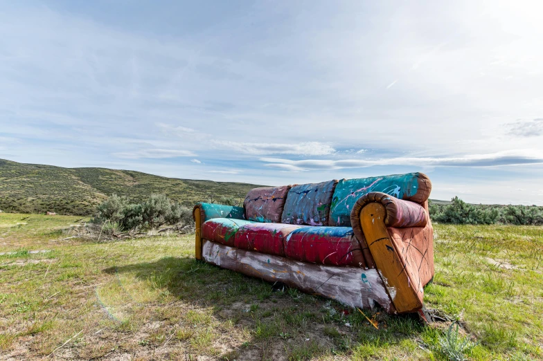 a couch is in the middle of a grassy field