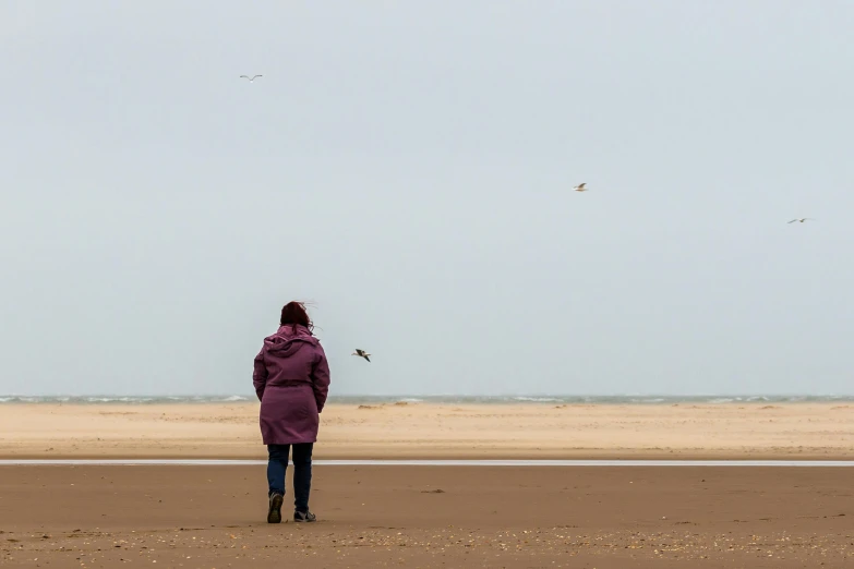 a person standing on the beach flying a kite