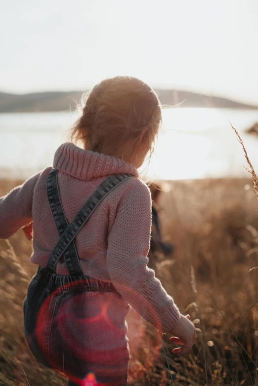 a little  standing in a field with tall grass