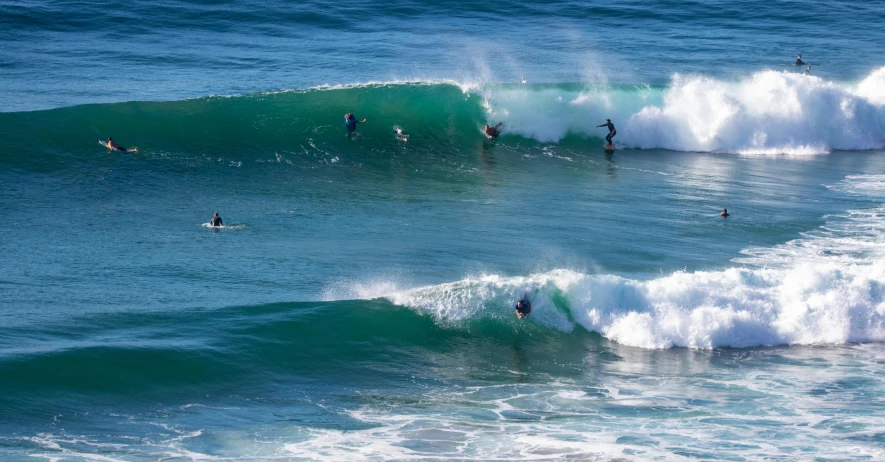 several people surfing in the ocean and people swimming on surf boards