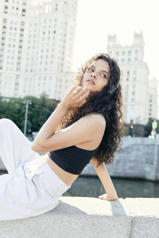 a young woman is sitting on concrete, looking to her left