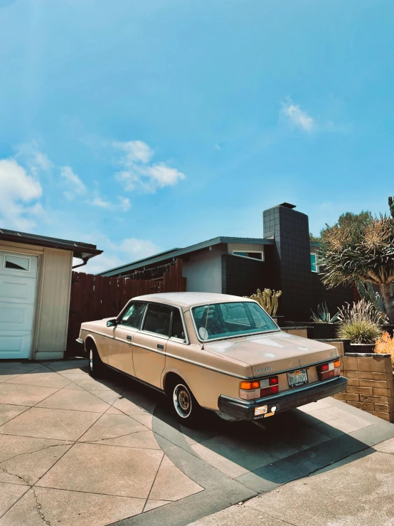 an old car parked on the concrete in front of a house