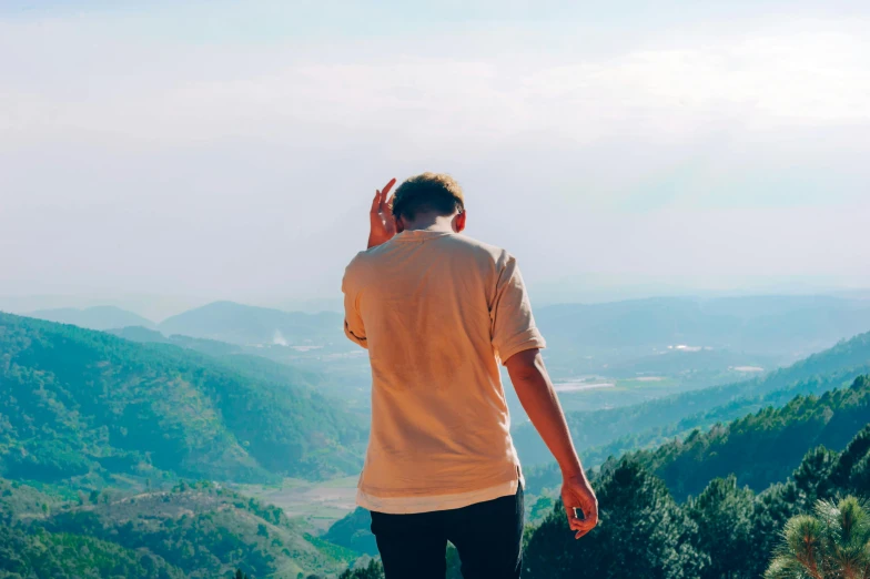 the man stands on the top of a mountain looking at the valley below