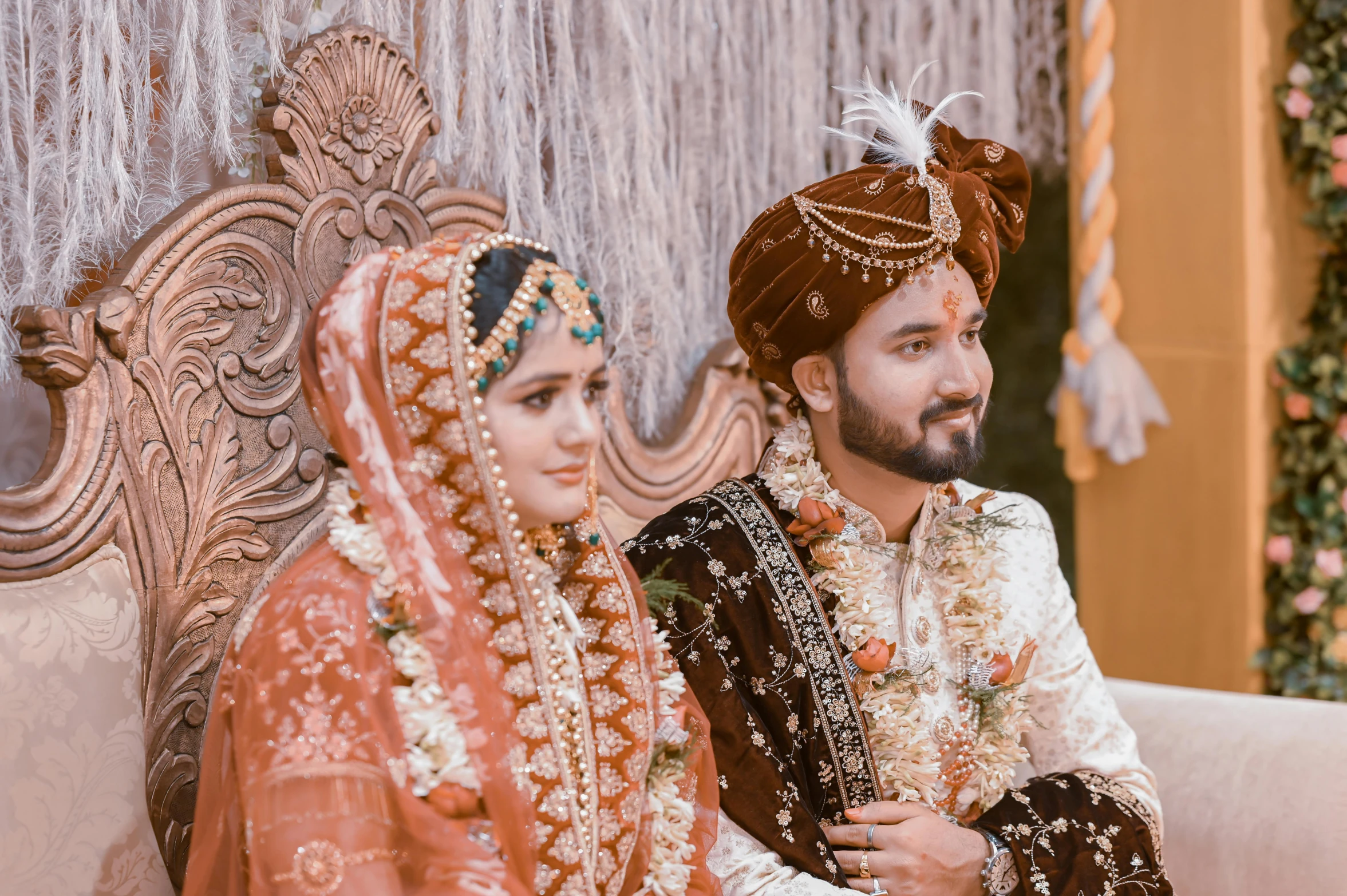 man and woman sit side by side wearing traditional indian outfits