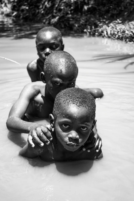 three children in the water of a stream