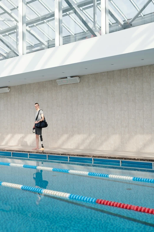 a young man is waiting near the blue swimming pool