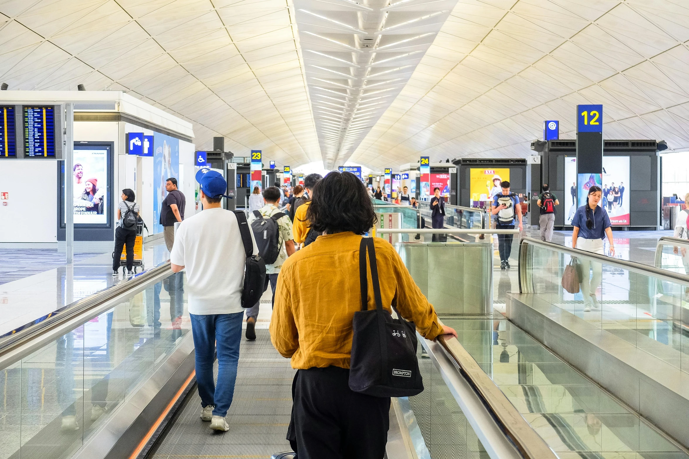 a group of people riding down an escalator with many people walking up and down it