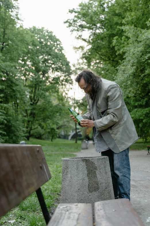 man looking at his phone and leaning on some benches