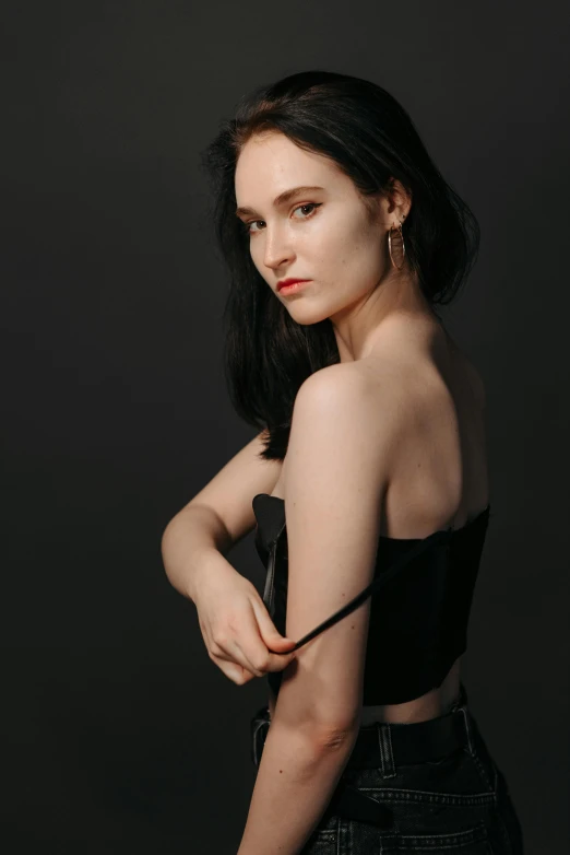 the model is wearing a dark dress with matching heels and earrings