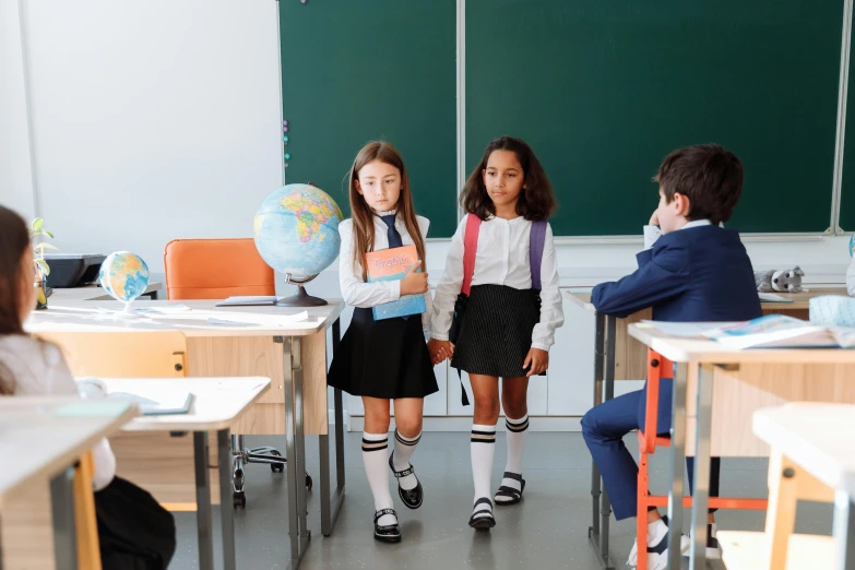 two girls and an older man sitting in their classroom