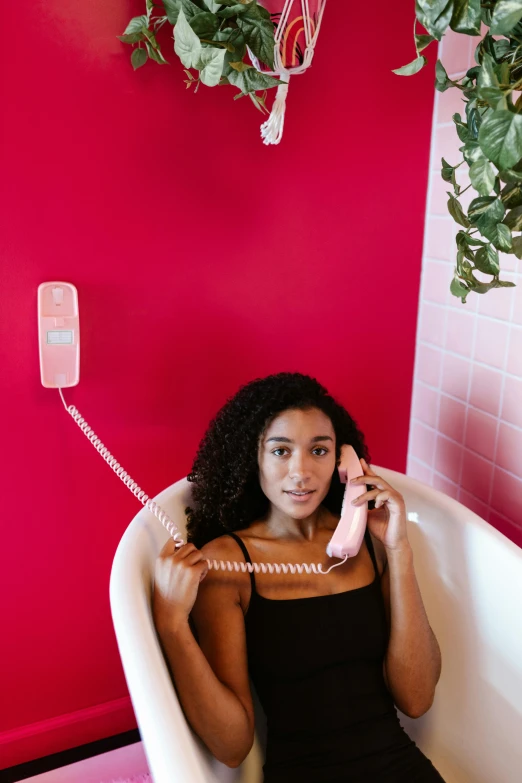 a woman sitting on the bathroom floor and talking on the phone