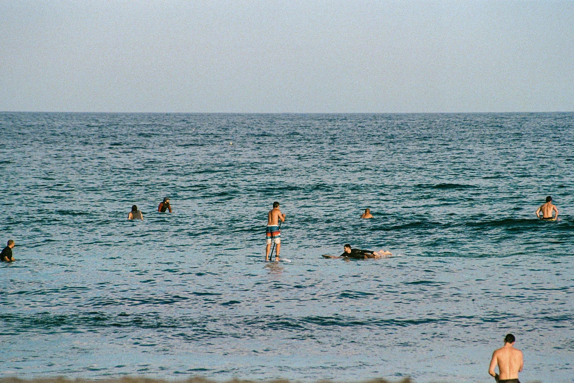 many people are standing in the water near the beach