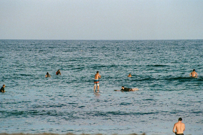 many people are standing in the water near the beach