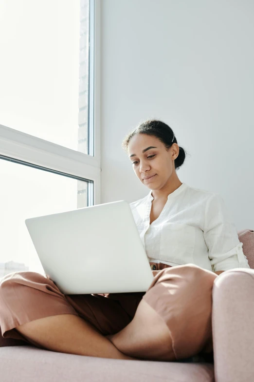 a woman is sitting on the couch with her laptop