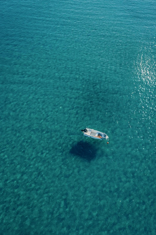 an aerial view of the blue ocean with a boat