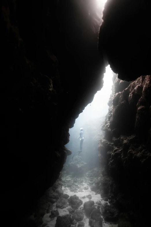 a person standing underneath some very thick rocks in the sea