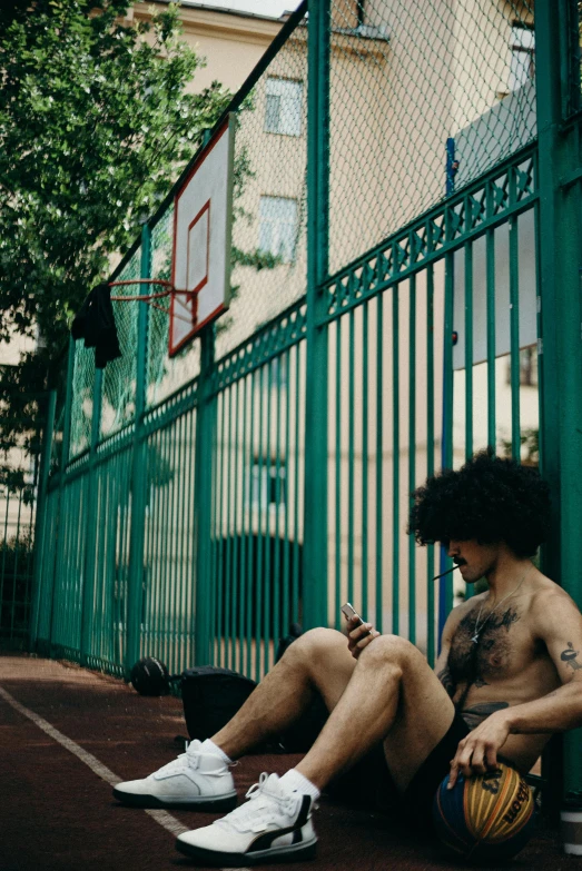 a man wearing tattoos sitting on a basketball court