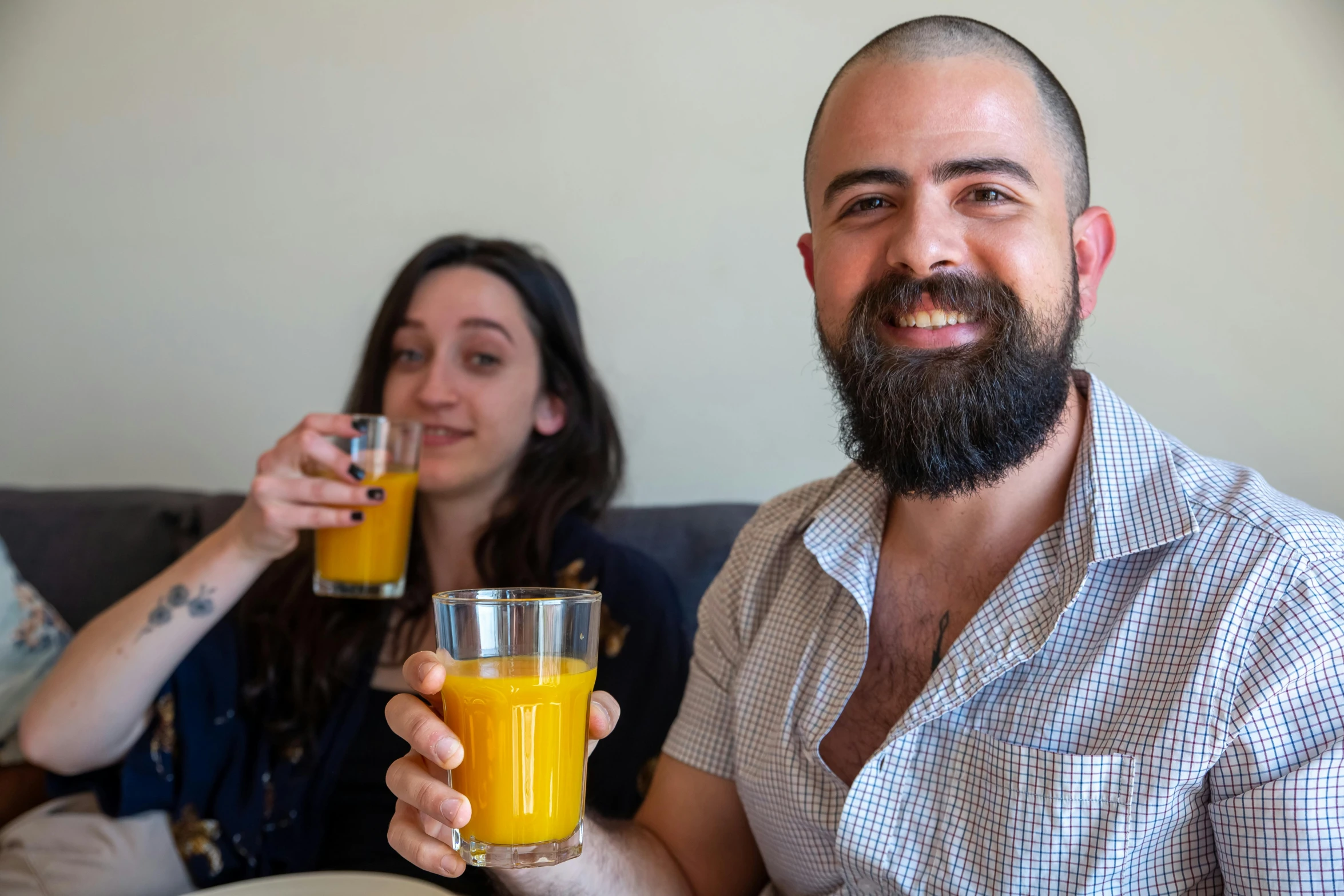 a man with a beard and a woman holding glasses of juice