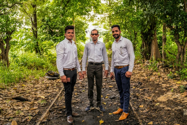 three men standing in a wooded area next to trees