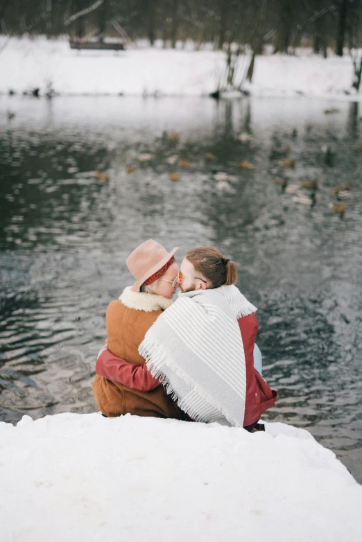 a woman is holding her child and sitting on a frozen pier by the water