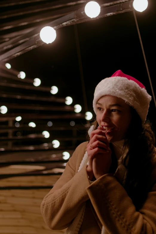 a woman wearing a santa hat and lighting in a room