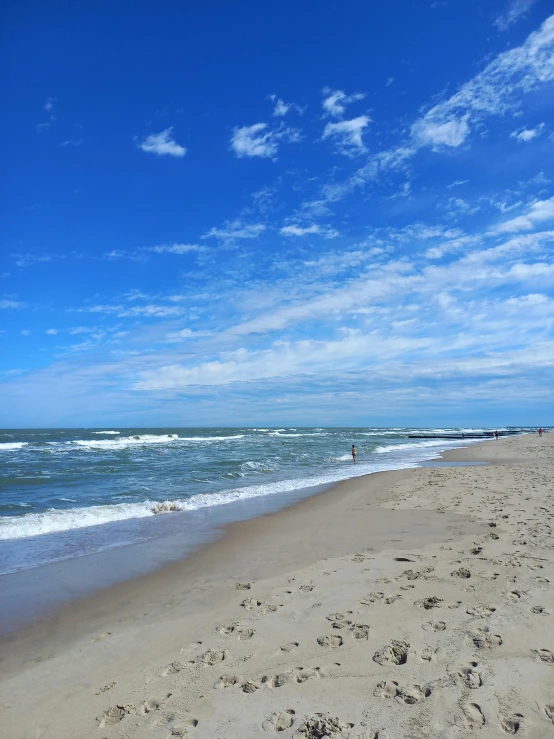 a sandy beach under a blue sky and clouds