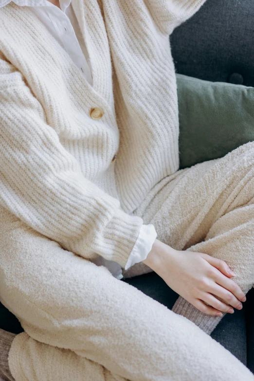 a woman in white sweater sitting down with her arms crossed