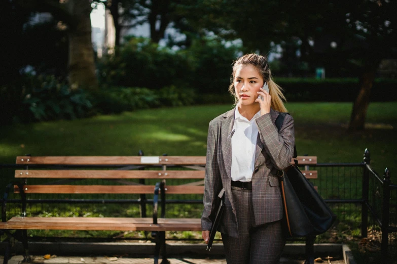 a woman is walking in the park on her cellphone