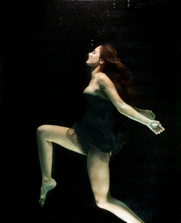 a woman swimming under water at night