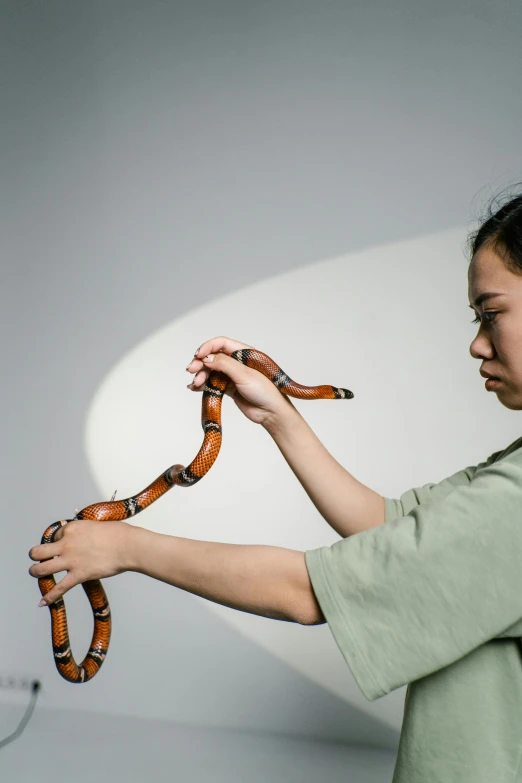 a woman is holding a snake in her hand