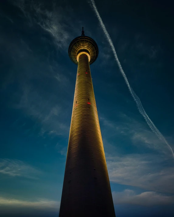 the tall tower is illuminated at night by a light pole