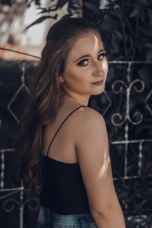 a woman is standing against a fence and posing