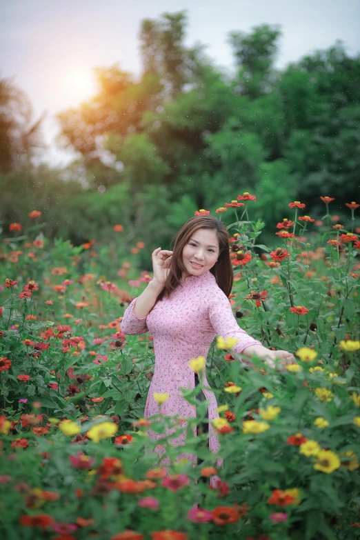 a girl in pink dress standing in field of flowers