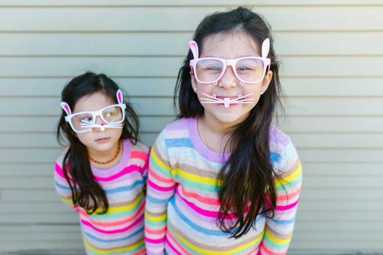 two small girls wearing glasses are standing next to each other