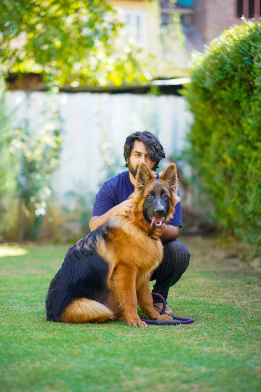 a person kneeling in a yard next to a dog