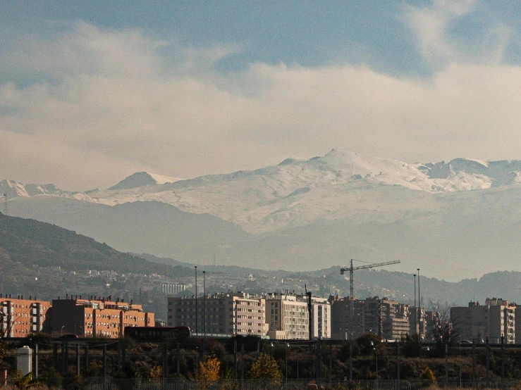 tall buildings in the foreground and snowy mountain tops in the background