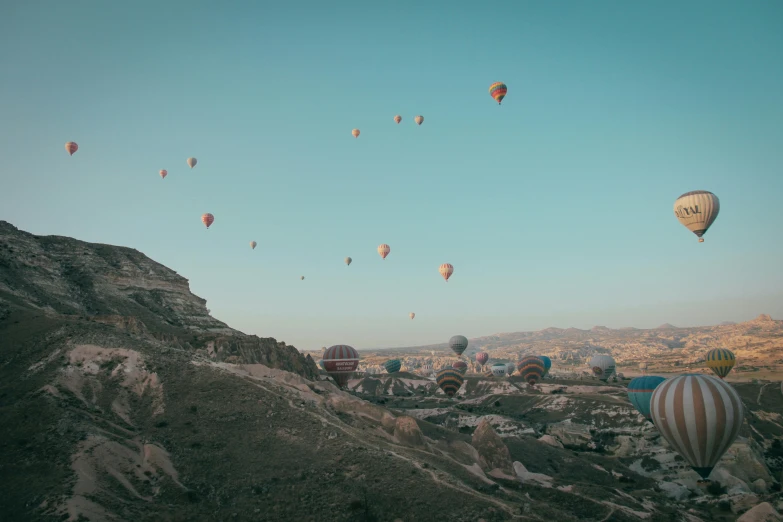 colorful balloons float above a rocky landscape against the blue sky