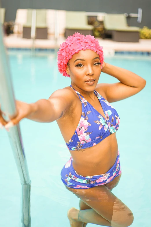 an attractive woman in a bathing suit leaning against a metal pole in a pool