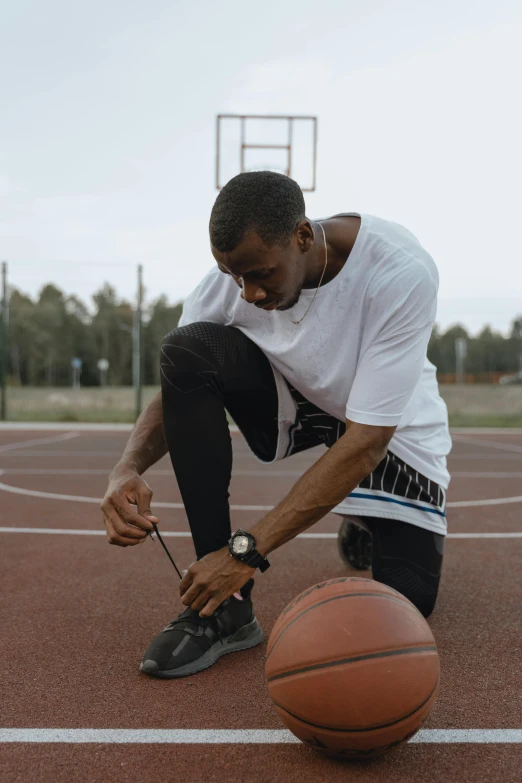 a person kneeling on a court near a basketball