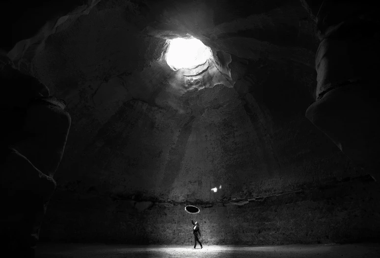 a dark cave with one lone figure standing alone