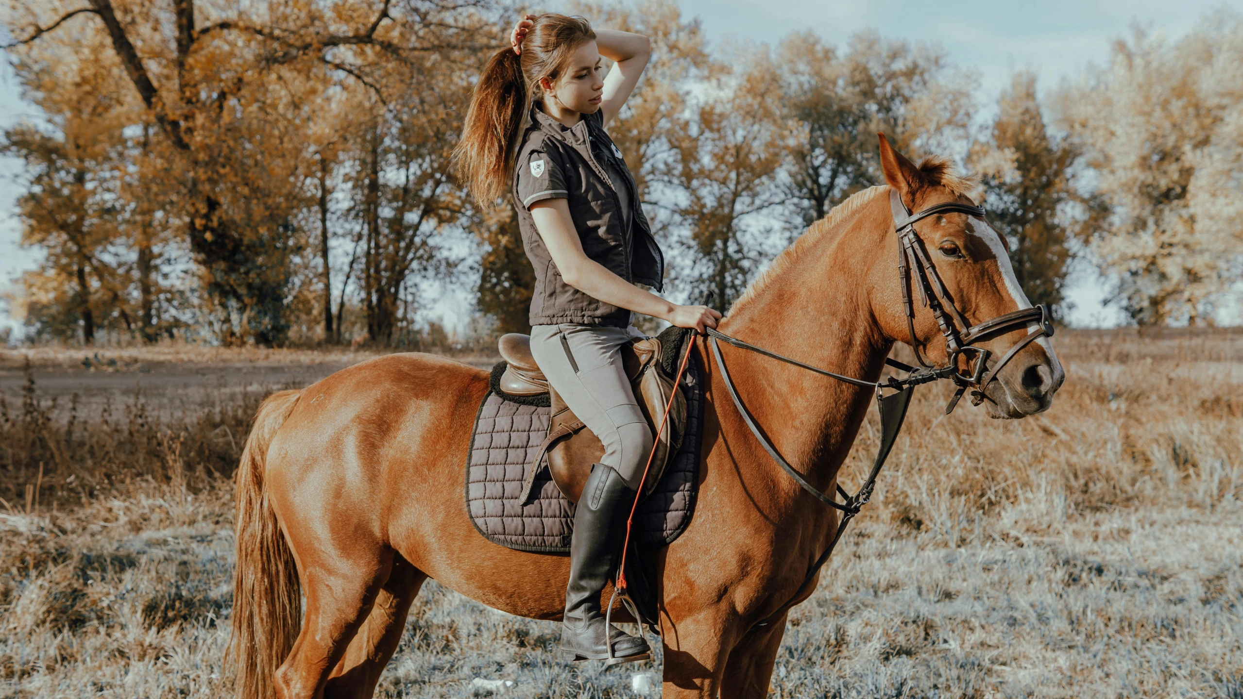 a girl wearing a hat is riding on a brown horse