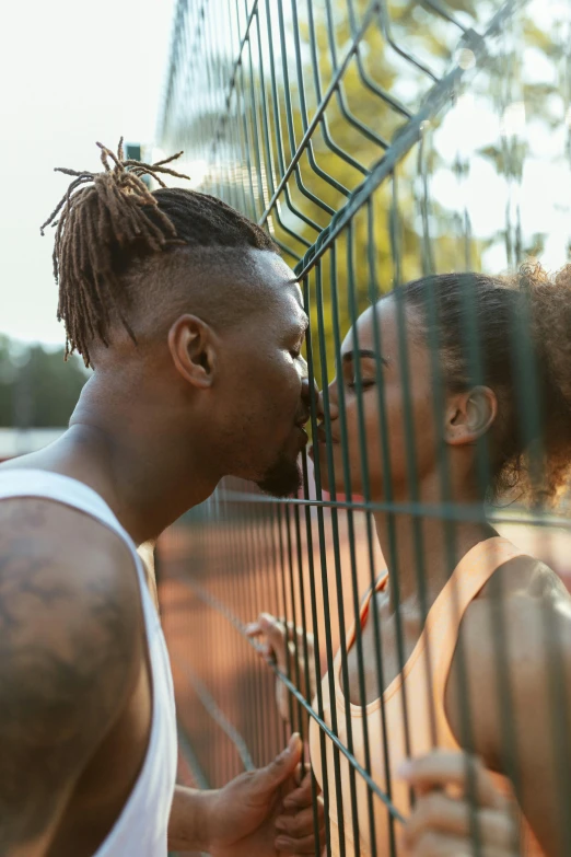 a man and woman touching noses in an open area next to a cage