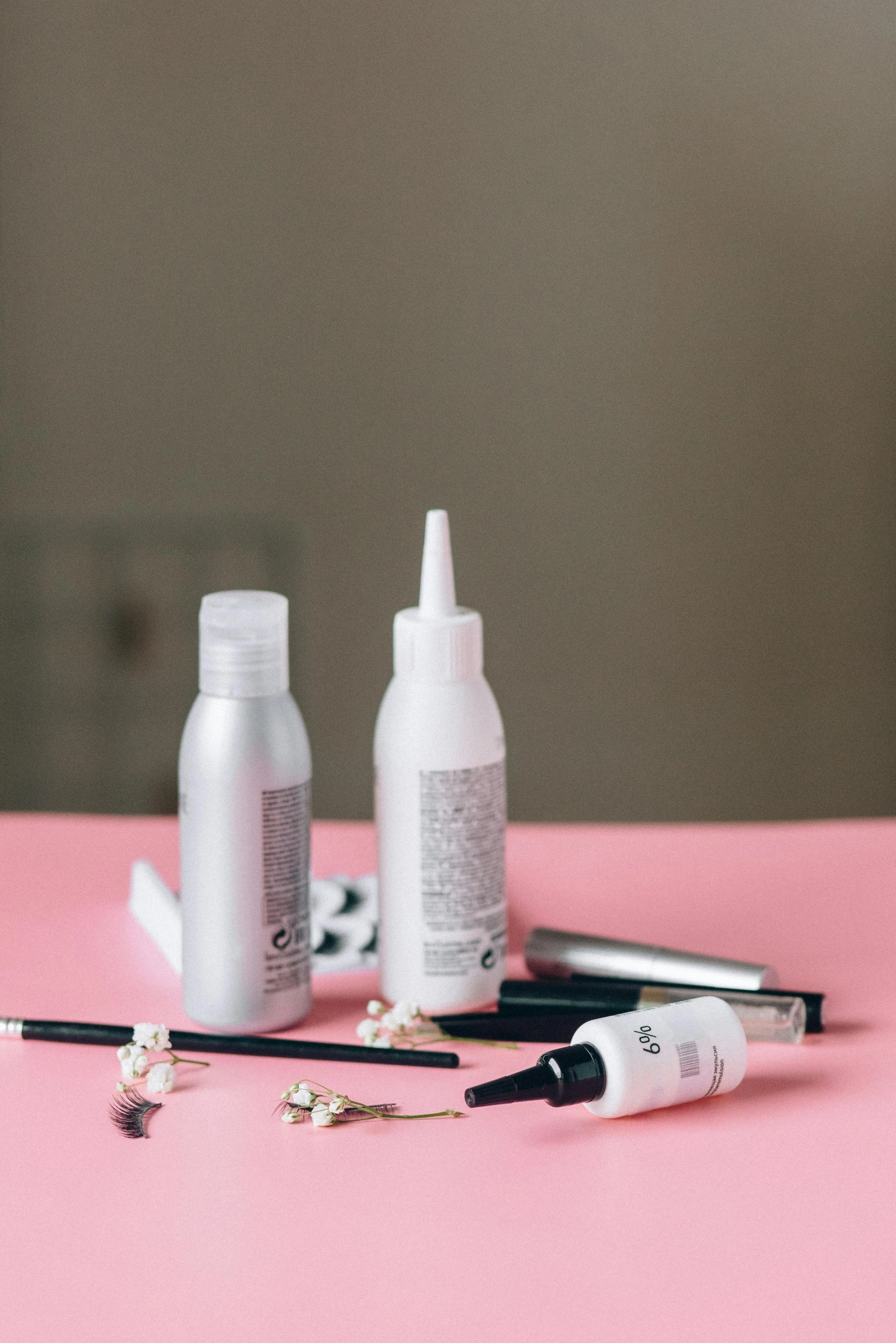 bottles of hair products sit on a pink surface