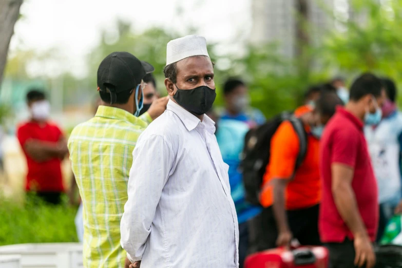 man wearing face mask and black hair standing with people