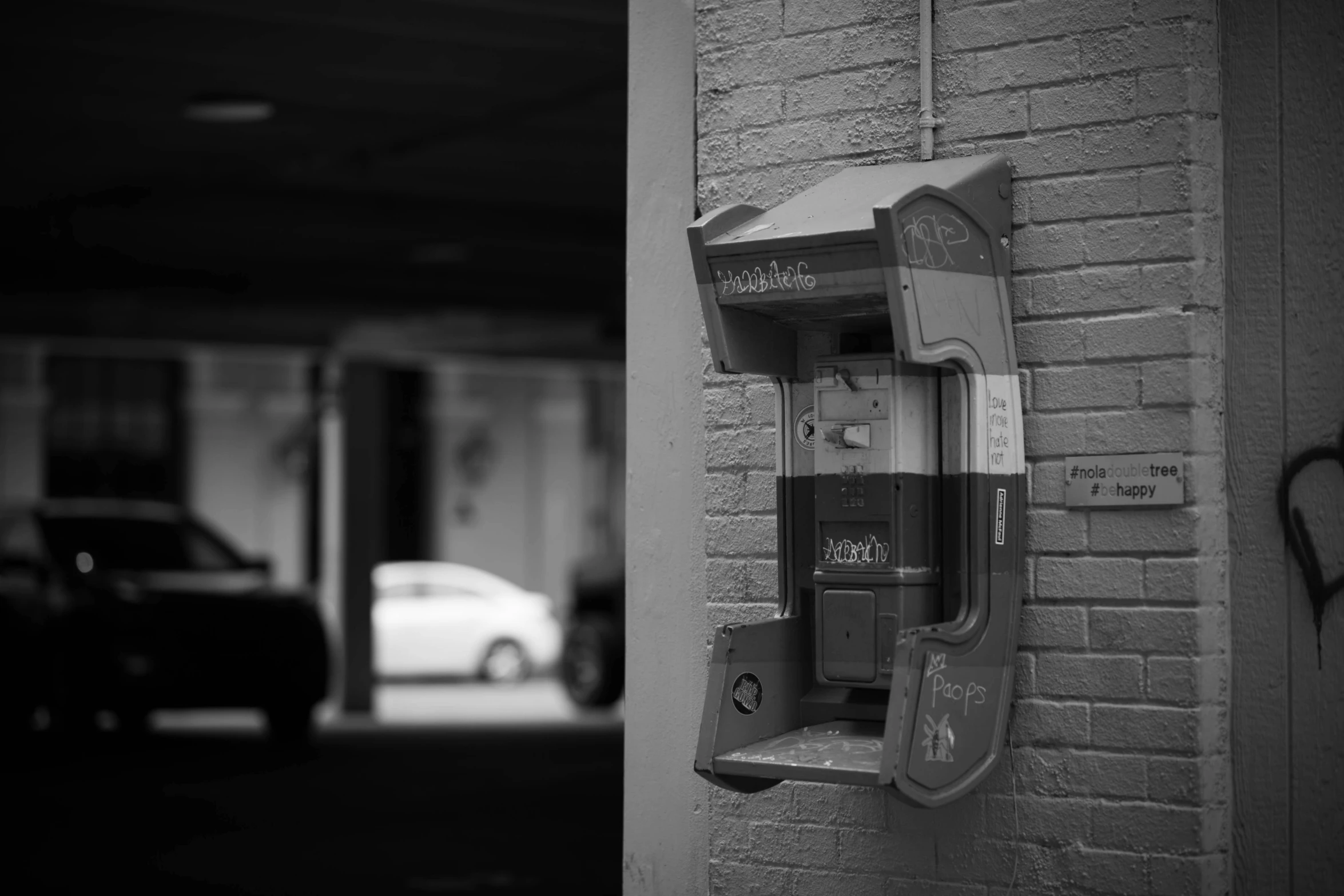 an old phone on the wall in a parking garage